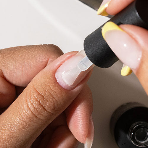 Applying base coat during gel manicure at home - photographed in Australia on model