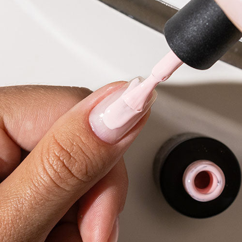 Applying base coat during gel manicure at home - photographed in Australia on model