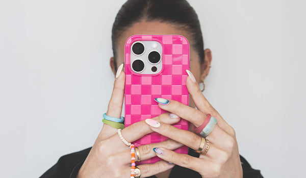 Person holding a pink checkered phone case with a white background - photographed in Australia